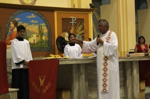 Frei Eraldo dando a benção de São Bras sobre as velas no altar